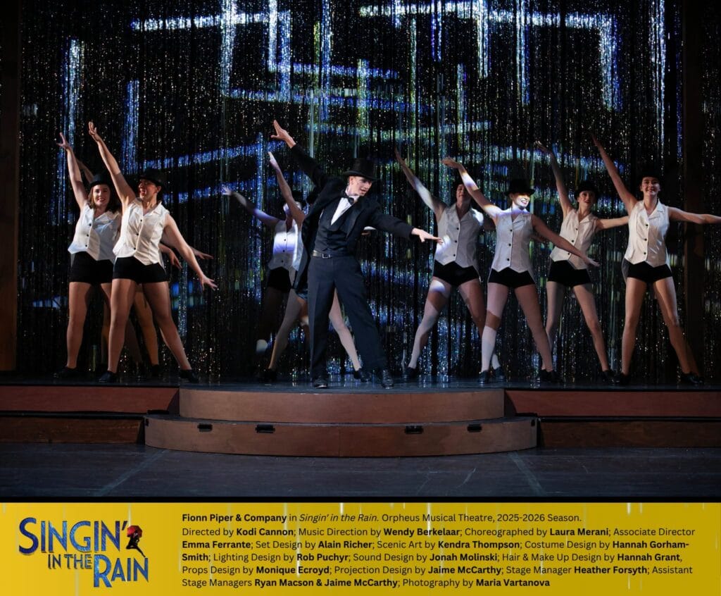 A group of dancers in black and white are dancing on a stage. In the center, is a man wearing a tux and top hat. He and the dancers all have their right legs extended at a diagonal, with their arms matching the line. At the bottom of the photo, in a yellow rectangle, is the "Singin' in the Rain" title and credits to the cast and crew.